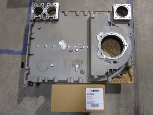 Produktbild eines Remeha Seitenglieds, metallisch, mit verschiedenen Öffnungen und Schrauben. Dazu ein brauner Karton mit Seriennummer, auf einem grauen Untergrund platziert.